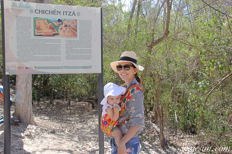 mexico-roteiro-8-dias-chichen-itza-com-bebe Mãe com bebê em sling em frente à placa de Chichén Itzá no México